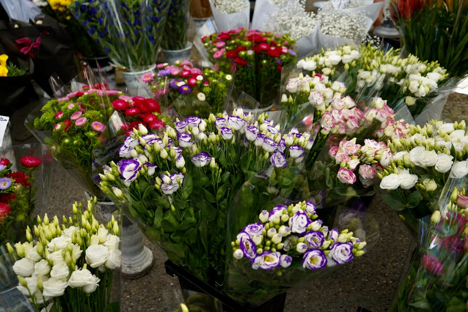 A close-up of a floral bouquet arranged with soft pink hydrangeas, creamy white roses and lisianthus, accented with dark green eucalyptus and other foliage. The flowers are neatly grouped, with the hy
